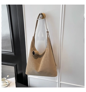 Detail view of khaki leather hobo bag with adjustable strap and decorative pendant charm
