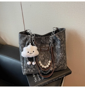 Detail of dark grey floral tote bag with brown leather straps and pearl chain charm