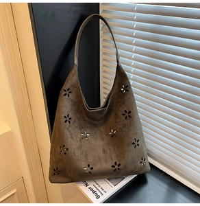 Detail of laser-cut floral patterns and sequin accents on brown suede tote bag