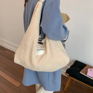 Detail of soft cream faux shearling hobo bag with SEEYOU label and cozy texture