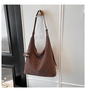 Detail of deep brown faux suede hobo bag with subtle leopard print and brand logo