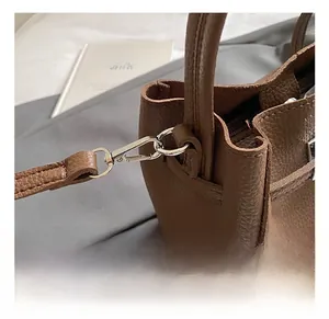 Dettaglio del gancio in metallo argento e pelle marrone martellata della borsa