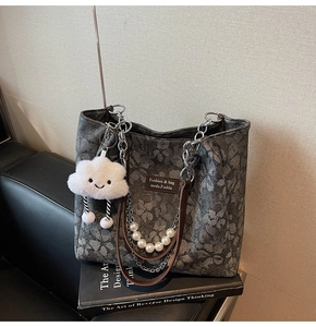Detailed shot of grey floral tote bag with silver chain handle and white cloud charm