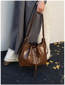 Close-up of brown quilted leather bucket bag featuring gold zippers and drawstring detail