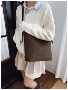 Detail of a dark brown vintage bucket bag with matte texture on a female model