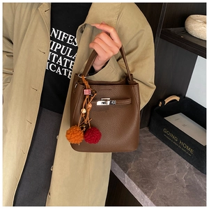 Close-up of leather bucket bag with silver twist lock and colorful tassel charm