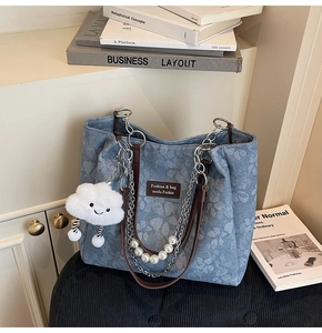 Close-up of floral denim tote bag featuring leather handles and pearl chain strap
