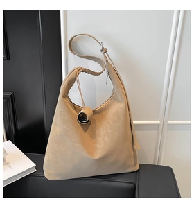 Detail of beige hobo bag with vintage pleated leather texture and a matching scroll charm