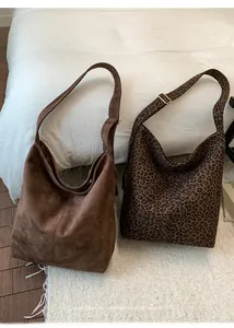 Detail of suede bucket bags showing wide straps with gold adjustable buckles
