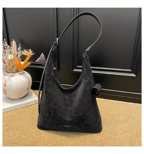 Detailed view of black matte leather Hobo bag on woven carpet with vintage home decor