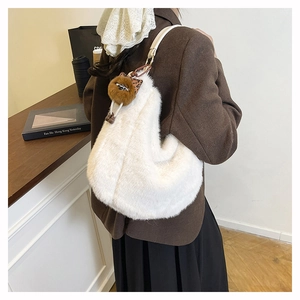 Détail d'un grand sac cabas en peluche blanche avec un charme de dessin animé porté