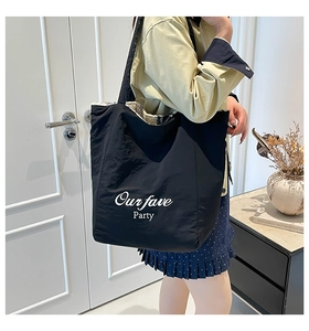Detail of black tote bag featuring nylon exterior and faux shearling lining with text