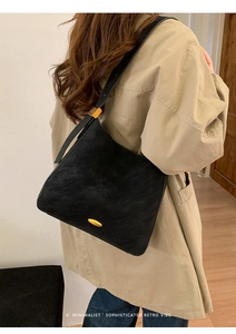 Detailed back view of minimalist black bucket bag with elegant gold metal hardware accents