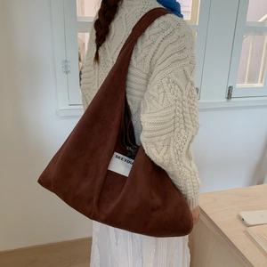 Detail shot of a dark brown suede hobo bag with an accent label on the side