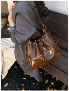Macro detail of brown quilted leather bucket bag with gold hardware and drawstring closure