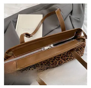 Détail de la fermeture éclair argentée sur le sac cabas léopard avec sangle en cuir