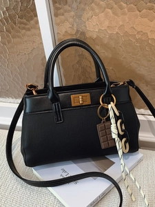 Sac seau noir chic avec fermoir doré et pendentifs design sur un livre vintage