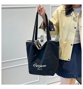 Detail of black nylon tote bag with faux shearling lining and Ourfave Party print
