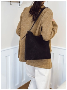 Detail view of a black suede bucket bag showing large capacity and soft material texture