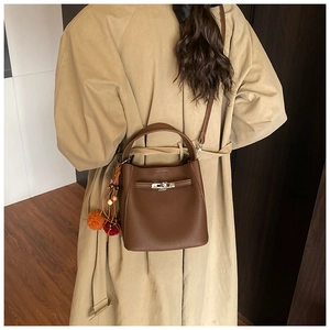 Detail of dark brown pebble leather bucket bag with silver twist lock and charm