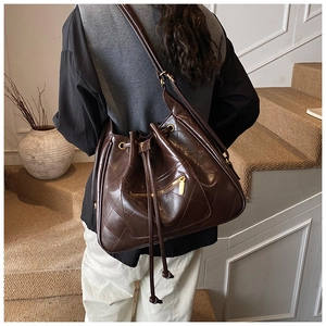 Detailed view of dark brown quilted bucket bag with gold hardware and drawstring detail
