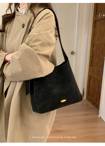 Close-up of minimalist black suede shoulder bag with an oval golden buckle and retro vibe