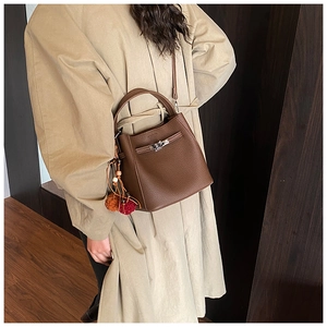 Detail of dark brown leather bucket bag with silver lock and colorful fur charm