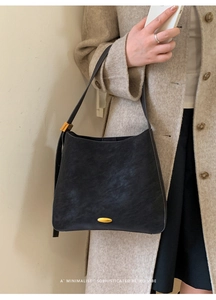 Detail of vintage black bucket bag with golden buckle on elegant beige wool coat