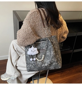 Detail of floral tote bag featuring pearl chain, metal strap, and white cloud charm