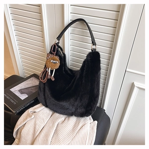 Détail du sac hobo en fausse fourrure noire avec breloque en peluche et ferrures dorées