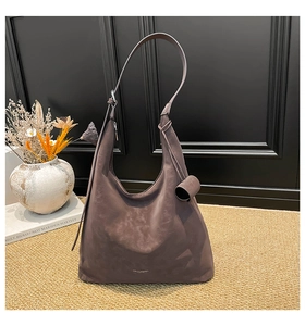 Close-up of violet-grey suede hobo bag with unique cylindrical charm and shoulder strap