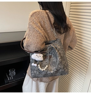 Detail of grey vintage floral tote bag with leather strap and pearl pendant accessory