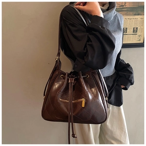 Detail of coffee brown quilted bucket bag with gold zipper and drawstring closure