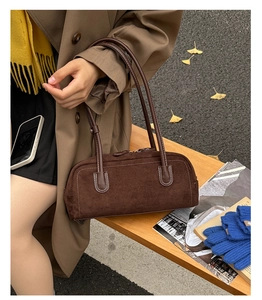 Close-up of vintage brown suede baguette bag featuring white contrast stitching details