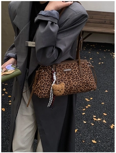 Détail du sac à main léopard avec charm ours en peluche et étiquette de mode