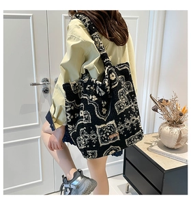 Detail of a large sherpa tote bag with white paisley floral patterns worn over the shoulder