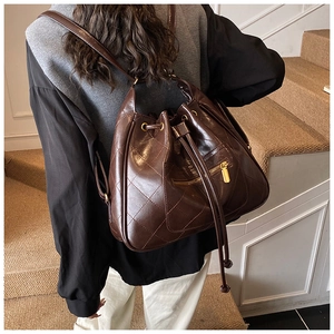 Detailed view of dark brown quilted backpack featuring vintage diamond patterns and gold zipper