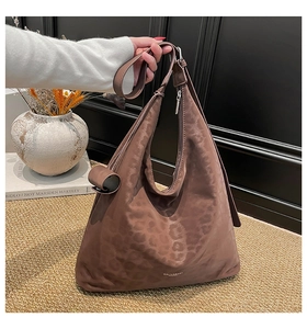 Detail of dark brown tote bag with animal texture and vintage brand logo design