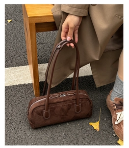 Detail of dark brown suede boston bag featuring long handles and silver metal zipper