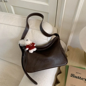 Detail of dark brown hobo bag with contrast stitching and cute puppy pendant