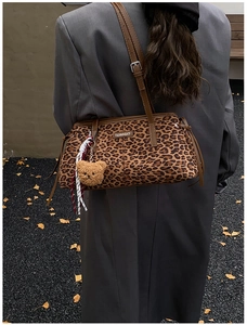 Détail du sac bandoulière léopard avec logo métallique et breloque ours en peluche