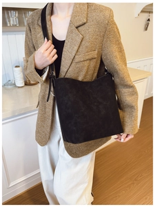 Detail of a vintage black bucket bag with a matte texture styled on a model's shoulder