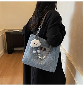 Blue denim floral tote bag detail with leather strap and plush cloud charm on shoulder