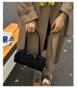 Street style shot of a black suede Boston bag paired with a trench coat and yellow scarf