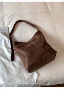 Detailed close-up of dark brown suede hobo bag with vintage vertical seam and wide strap