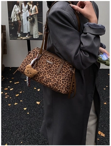 Détail du sac cabas léopard avec un pendentif ours en peluche et bandoulière en cuir brun