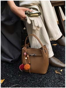 Close-up of brown pebbled leather bucket bag with silver turn-lock and colorful tassel