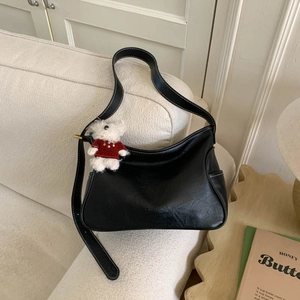 Detail of black crescent shoulder bag with white contrast stitching and bear charm