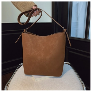 Detail view showing textured brown suede material and fine stitching on the bucket bag