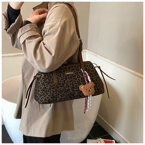 Détail du sac léopard avec plaque métallique et pendentif en peluche en forme d'ours